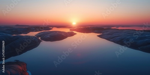 A beautiful sunset over a calm lake with a reflection of the sun