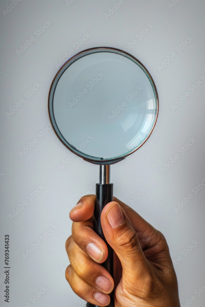 A hand holding a magnifying glass with a clear lens A hand holding a magnifying glass with a clear lens