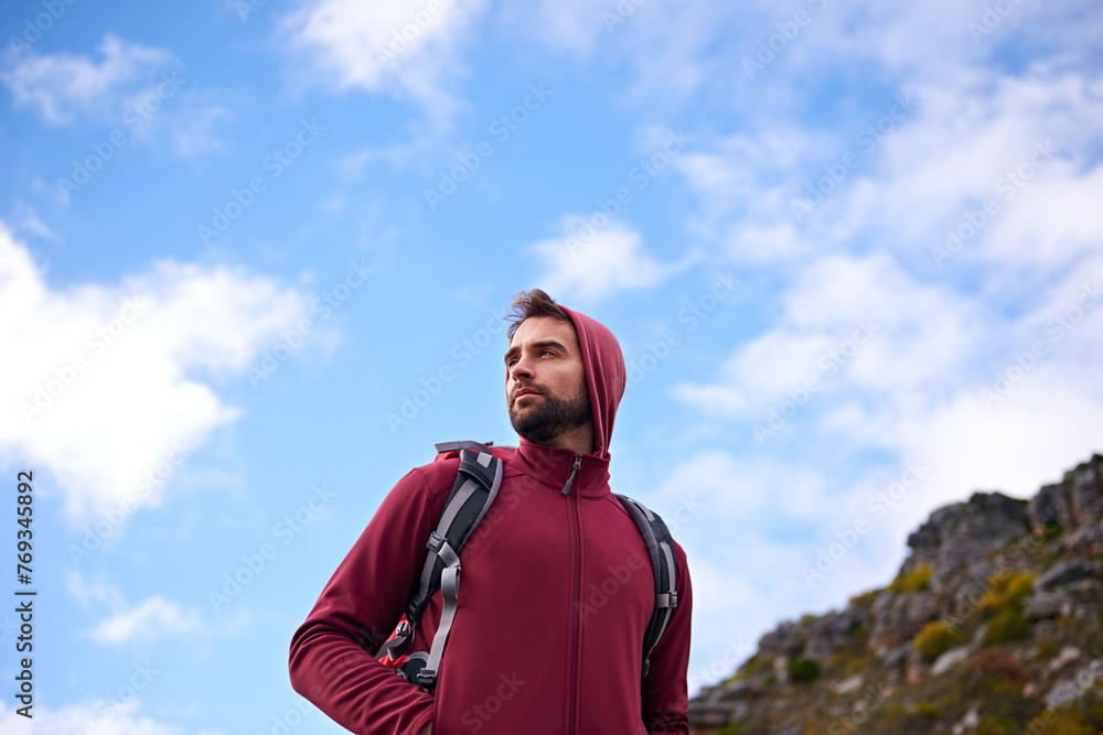 Blue sky, hiking and man on mountain, thinking and outdoor in nature for adventure, peace and travel. Contemplation, calm and male person in vacation, thoughtful and journey for holiday and backpack