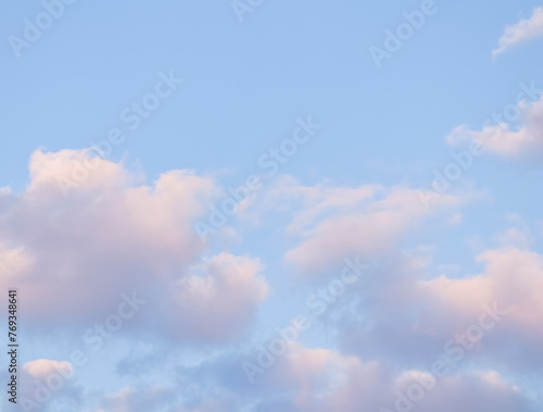 Blue sky background with pale pink clouds at sunset