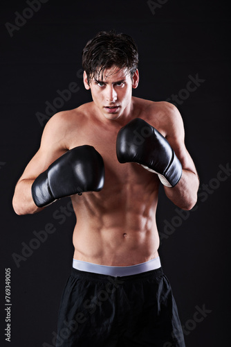 Man, portrait and boxing gloves in studio for workout fight or martial arts training or performance, black background or challenge. Male person, face and sports exercise or fitness, athlete or mockup © peopleimages.com