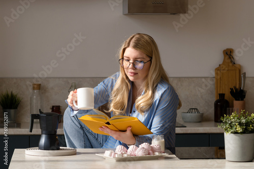 Woman reading book in morning kitchen scene