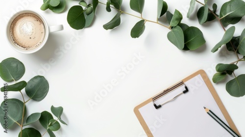 Top view office workspace with eucalyptus leaves, clipboard, and coffee cup on white background - flat lay concept for ideas, notes, or planning photo