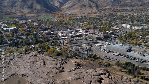 A spectacular, orbiting drone shot of a hiker on top of viewpoint looking over the Coors Light factory, the School of Mines college campus, in Golden, Colorado, during the colorful fall season. photo