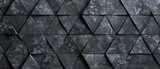 Abstract geometric mosaic of dark black and anthracite gray stone concrete tiles. Features fluted triangular patterns for textured wallpaper.