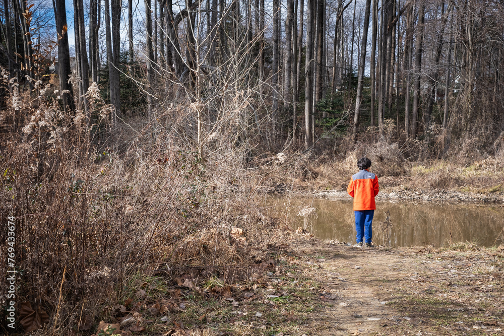 Young boy fishing from shore of lake in winter. Young boy fishing from shore of lake in winter.