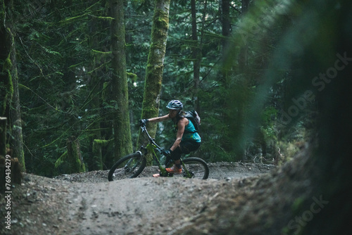 Woman riding mountain bike on trail in the forest