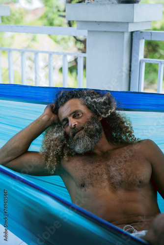 Arabic palestinian man with long curly hair is resting in a hammock.