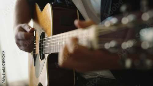 Lifestyle concept. Young musician playing guitar in living room at home on this weekend. Relaxing with song and music. Man having fun playing acoustic guitar