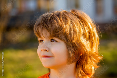 Cute little boy portrait closeup. Blonde child. Portrait of happy kid outdoors. Little boy walks on outdoors, spring weather, sun is shining, child relaxing under sun. Child, boy, spring, sun