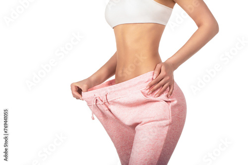 Dieting. Woman showing slim body after sport trainings, healthy eating. Weight loss concept. Thin woman in big pants, weight loss concepts. Slim girl wearing oversized pants. Woman shows weight loss
