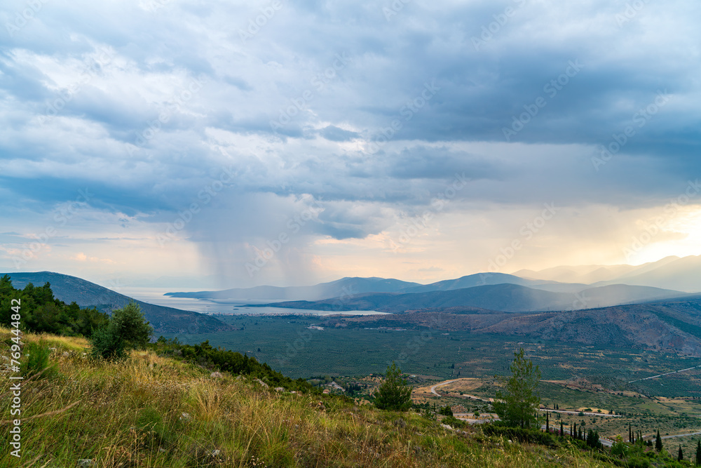 Delphi, Greece. Clouds with rain over the valley. After sunset the clouds clear and night falls. Northern coast of the Gulf of Corinth, Itea Bay