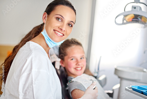 Young girl and dentist with smile in office on chair, appointment or results in consulting room. Professional, child and dental work, oral hygiene or working or care with tools, patient or calm photo