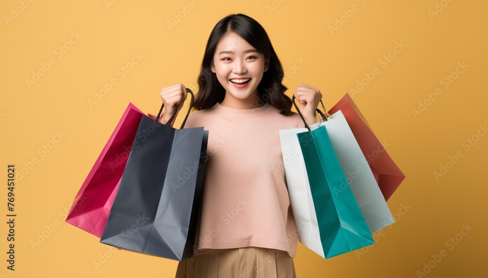 Portrait of Cheerful Asian woman holding shopping bags isolated over yellow background Portrait of Cheerful Asian woman holding shopping bags isolated over yellow background