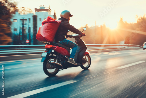 Courier using scooter with a cube-shaped delivery bag moving fast on motorway road to city photo