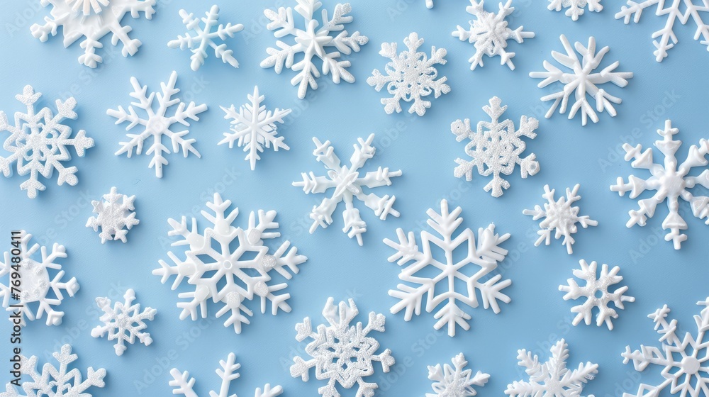 Snowflakes in white falling on a soft blue background creating a winter theme Snowflakes in white falling on a soft blue background creating a winter theme