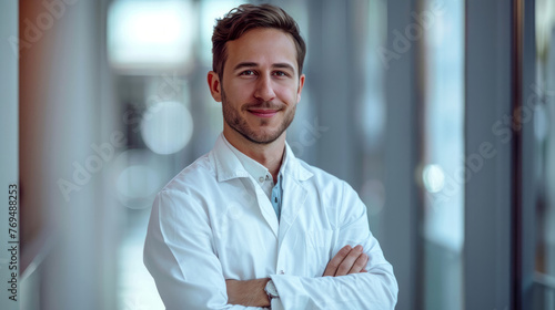 Portrait of a smiling male doctor standing with arms crossed in hospital corridor