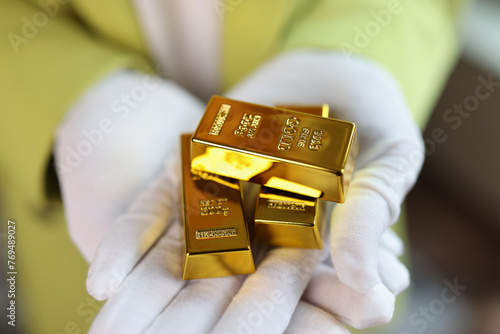 Gold bars in gloved hands close up.