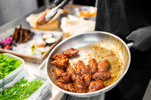 A skilled chef prepares glazed chicken wings in a bustling kitchen, surrounded by fresh ingredients. The vibrant scene captures culinary artistry and expertise
