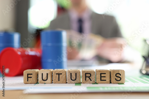 Word futures collected from wooden cubes with oil barrels and blurred business person in background.