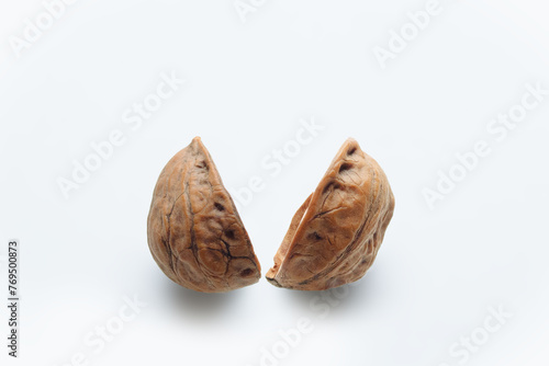 Broken walnut shell into two on white background.