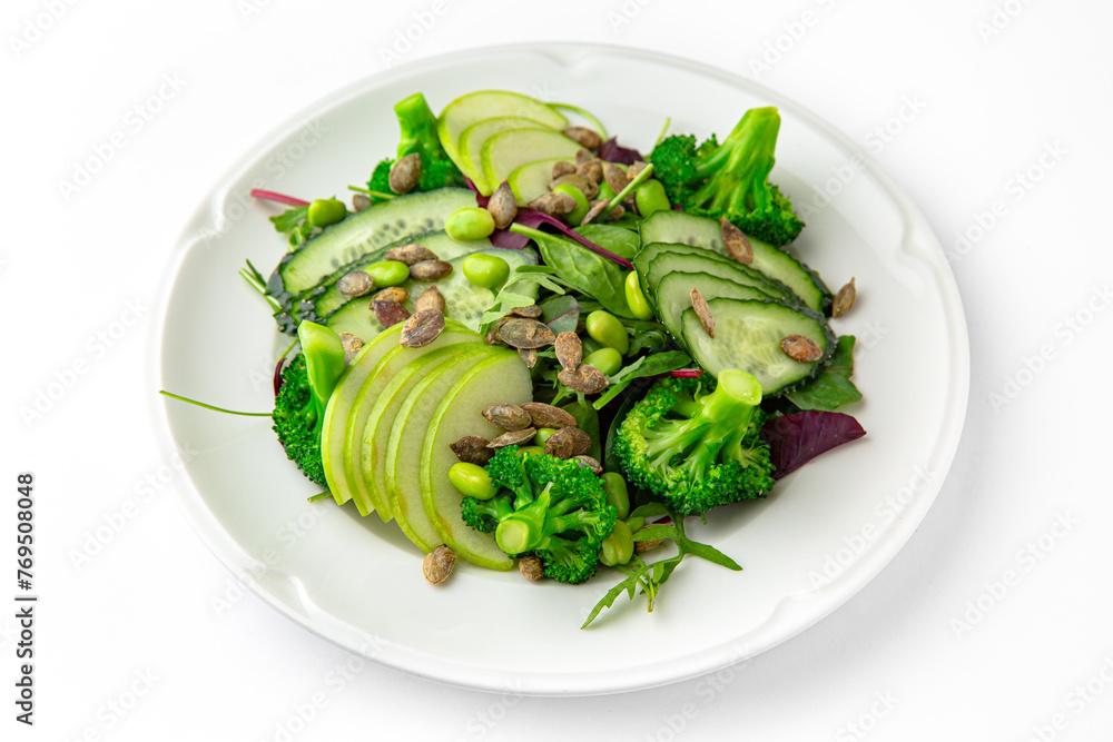 Vegetarian low-calorie salad of green vegetables, fruits and seeds on a white plate. Banquet festive dishes. Gourmet restaurant menu. White background. Vegetarian low-calorie salad of green vegetables, fruits and seeds on a white plate. Banquet festive dishes. Gourmet restaurant menu. White background.