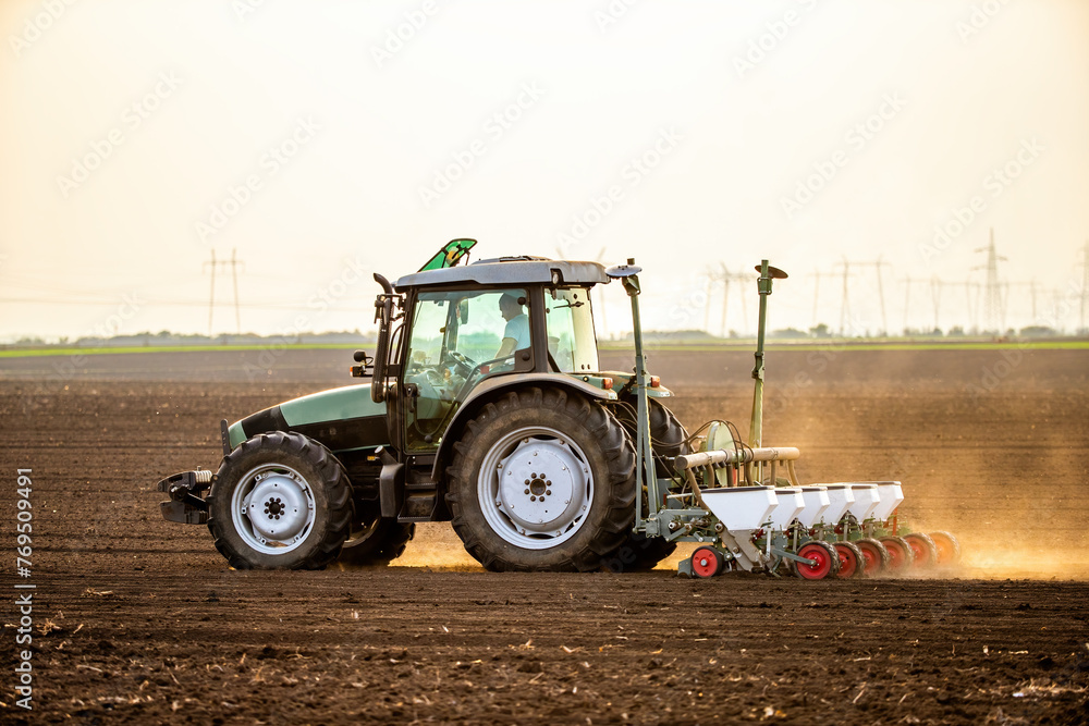 Obraz premium Modern tractor seeding, planting agricultural field at dusk