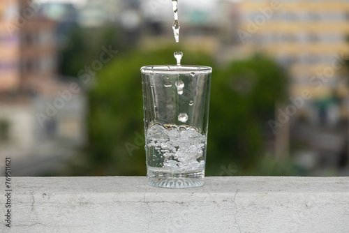 Bubbles are formed when water is poured into a transparent glass placed on the outdoor wall. Fresh drinking water flows into the glass.