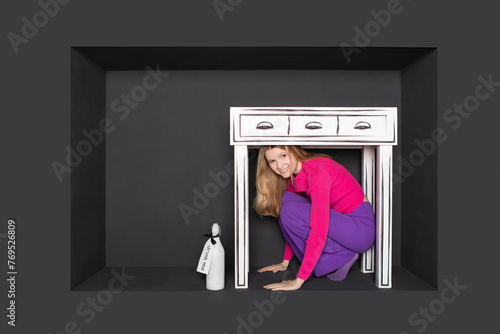 Teenage girl squatting below table in alcove over black background photo