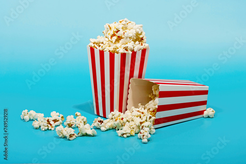 Red striped bucket with popcorn over blue background photo