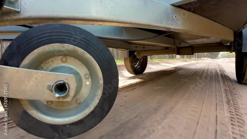 Trailer wheels rotation on sandy road. Car driving for cargo delivery. Bottom view, camera mounted beneath car chassis. Wheel rotation, spinning tyres. Freight Transporting using lightweight photo