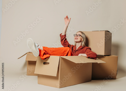 Smiling businesswoman sitting in carton box and day dreaming against white background