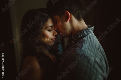 Close-up of a tender couple embracing in a dimly lit room. Intimate and romantic moment concept for design and print. Cinematic portrait with focus on faces and copy space