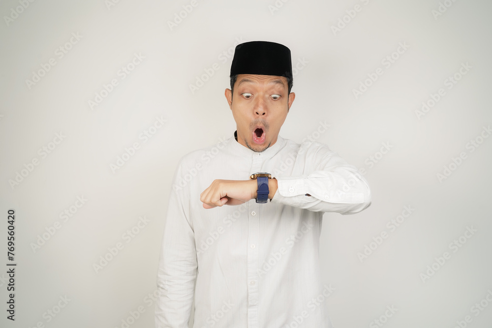 Asian Muslim man Wow face shocked expression looking at watch in copy space on isolated background - obrazy, fototapety, plakaty 