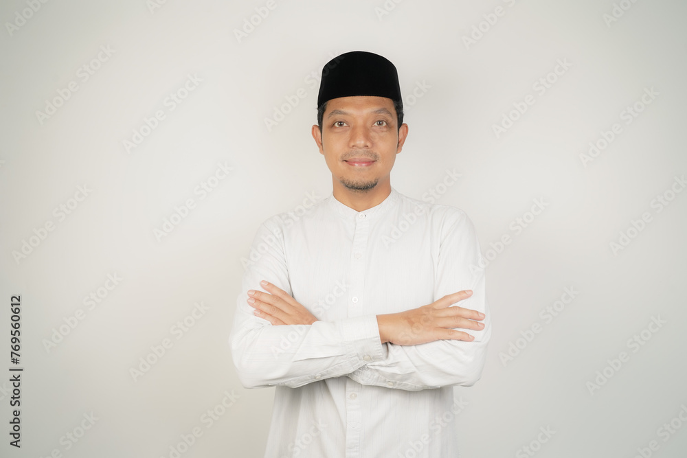 Happy and confident asian muslim man standing with crossed arms on white background - obrazy, fototapety, plakaty 