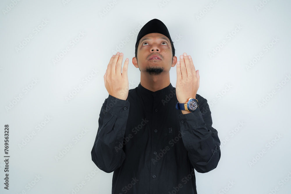 Asian muslim man is praying with hands up, copy space on isolated background - obrazy, fototapety, plakaty 