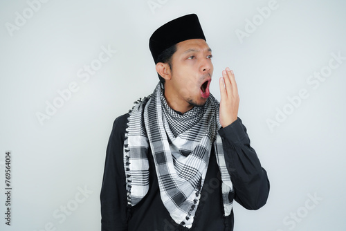 asian muslim man covering his mouth with hand or bad breath, wearing Arab turban sorban on isolated background photo