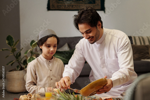 Muslim Man Sharing Dish With His Son photo