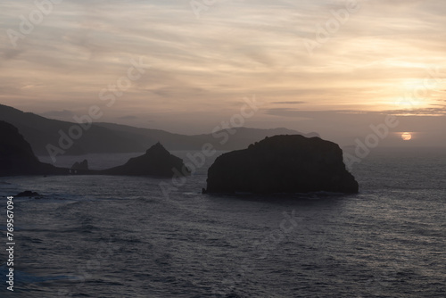 A serene sunset over the ocean  highlighting silhouetted islands and illuminating the sky with soft  warm hue