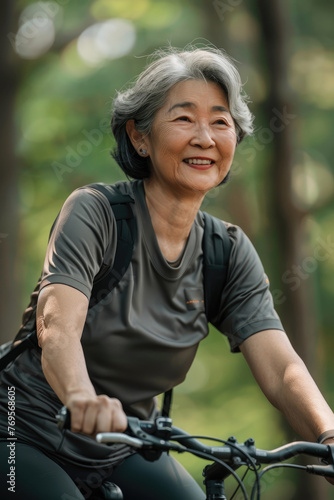 Happy asian elderly woman riding bicycle. She is leading an active lifestyle. Active old age concept