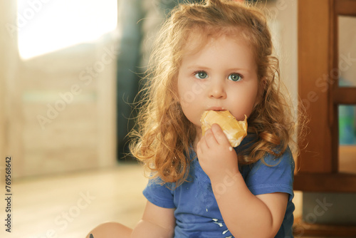 Lovely little girl sitting on the floor and eating ice cream. Summer mood, beautiful child with big green eyes and red hair. Happy childhood and motherhood