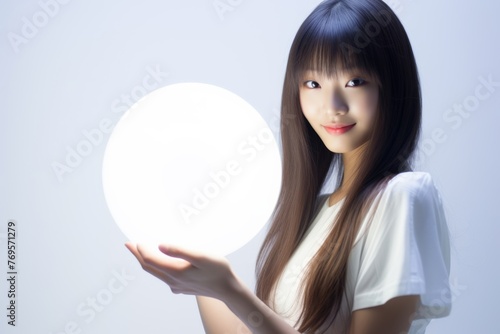 Cute woman with LED round flash lamp in white glow. Moon lamp turn on and hold by two hands. Generative AI. © Surachetsh
