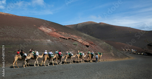 Caravan of camels with tourists in Timanfaya National Park, Lanzarote, Canary Islands, Spain