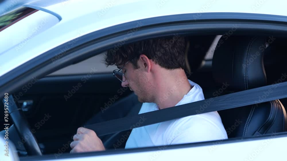 Young Caucasian man in glasses sitting on car with an open window while fastening seat belt Transport, safety and lifestyle concept. Slow motion Young Caucasian man in glasses sitting on car with an open window while fastening seat belt Transport, safety and lifestyle concept. Slow motion