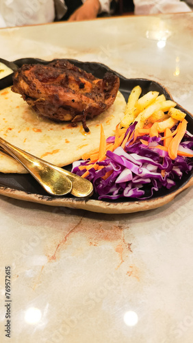 dajaj mashwi, oven roasted chicken typical arab dish served with 2 khubus (pita bread), french fries, closeup of salad, chili sauce and thum with empty space above the bottom photo