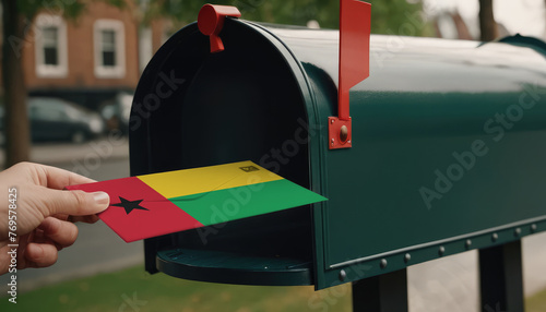 Close-up of person putting on letters with flag Guinea-Bissau in mailbox