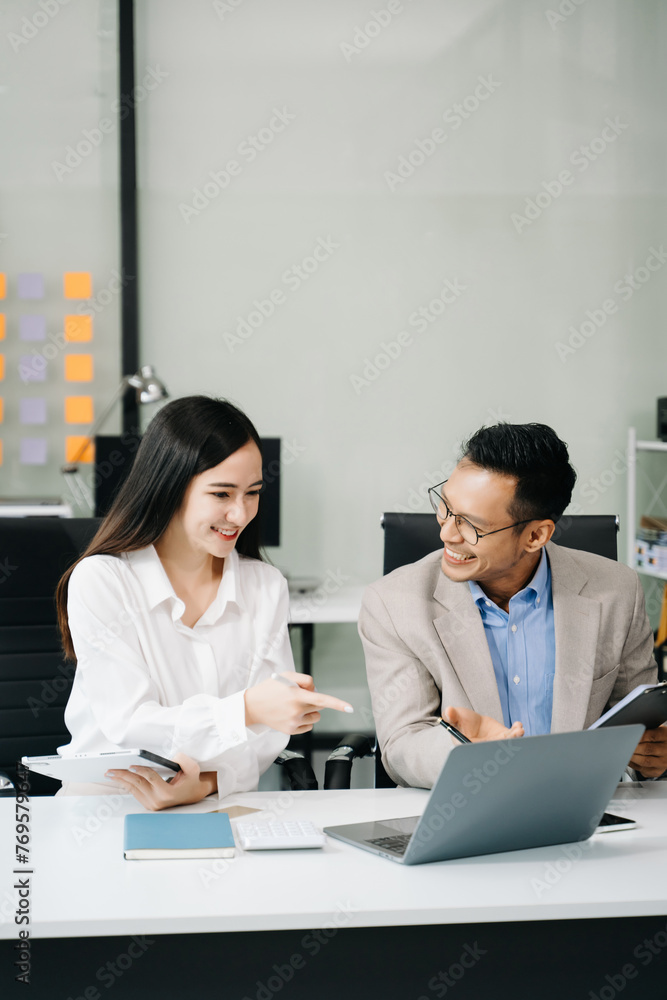 Two business workers talking on the smartphone and using laptop at the office.. Two business workers talking on the smartphone and using laptop at the office..