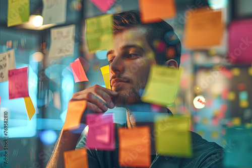 A young entrepreneur organizing ideas with sticky notes on a glass wall, planning and strategizing