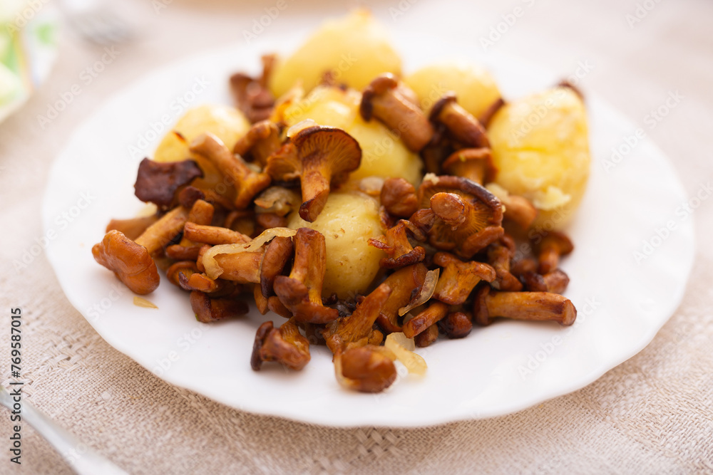 Delicious fried chanterelle mushrooms with new potatoes on a white plate