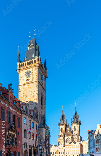 The historic clock tower stands tall against a clear blue sky in Prague Old Town Square, with other Gothic architecture visible in the background. Prague, Czechia